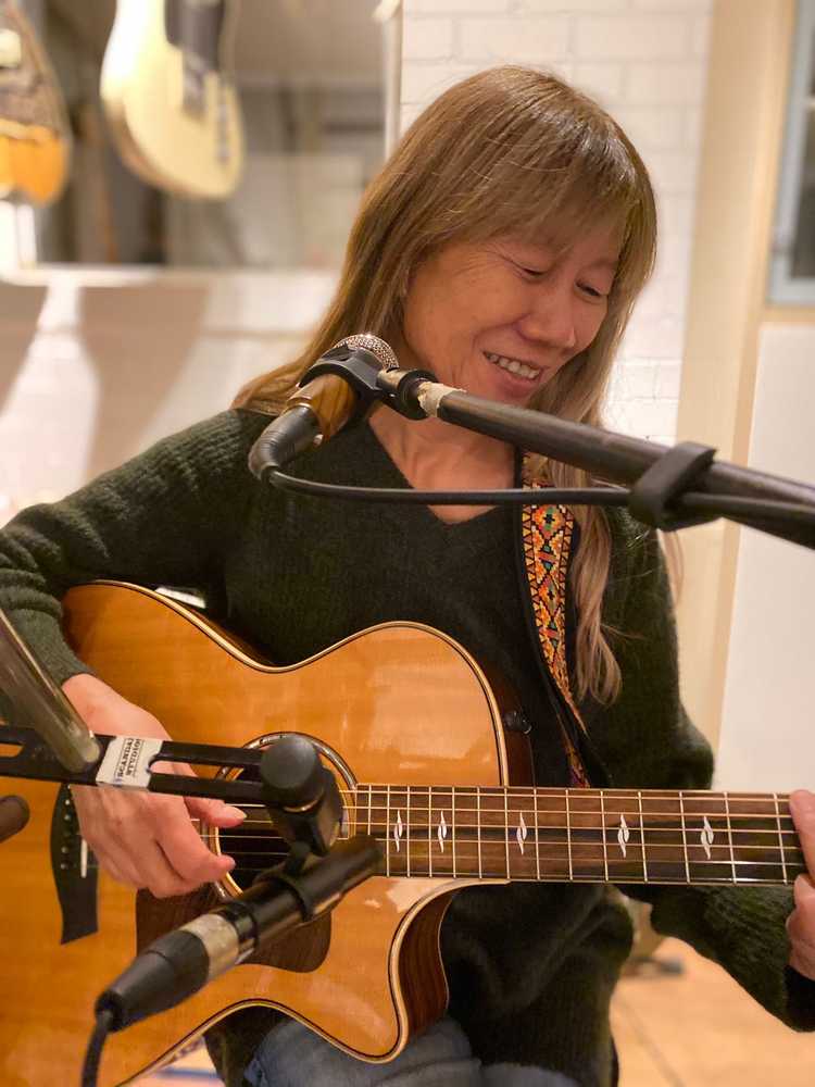 Photo of Sioe Tio sitting down with her guitar in her hands